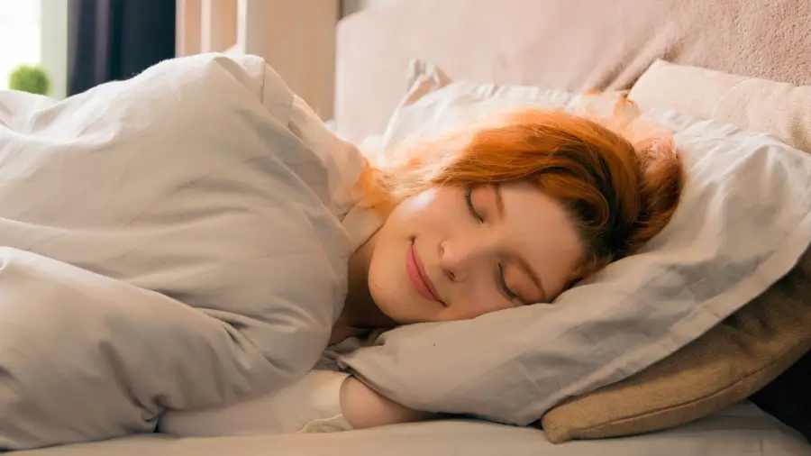 Young red-hearded woman sleeping happily in her cozy bed